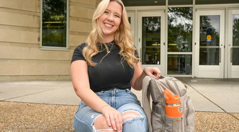 A woman sits on some steps in front of a building on ODU's campus. 